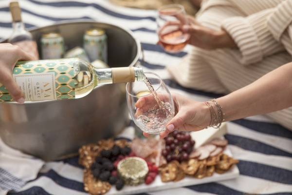 All the picnic essentials on a picnic blanket with a glass of wine