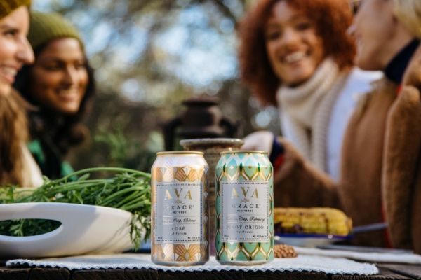 An outdoor dinner party with AVA Grace wine cans in the foreground 