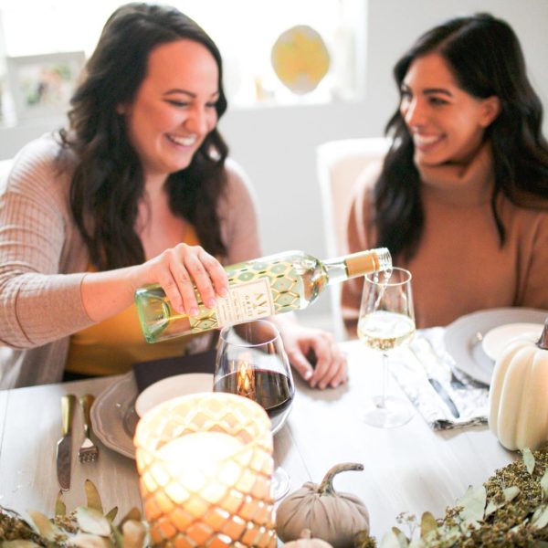 Two friends sharing a glass of AVA Grace Pinot Grigio with fall inspired tablescapes