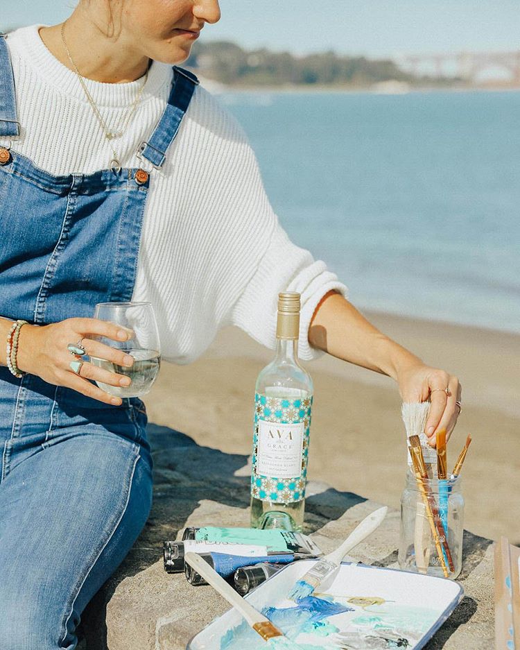 Women enjoying a glass of AVA Grace Pinot Grigio while painting by the bay.